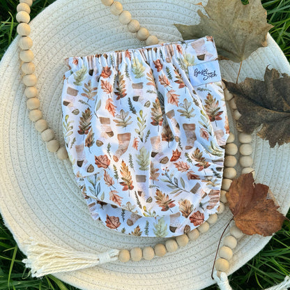 Cozy Beige Stocking Socks on a Tan Background with Leaves and Pine Sprigs