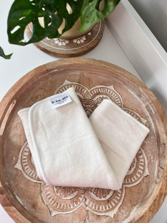 3-Layer Hemp Trifold Cloth Diaper Insert. Featured on a wooden coaster with plant in background.