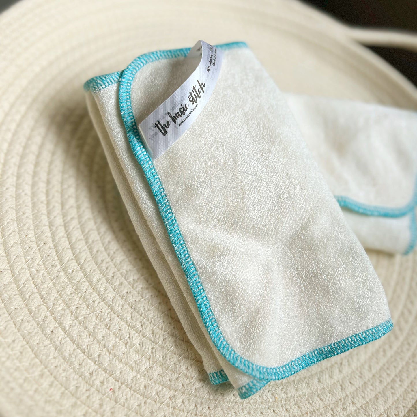 Bamboo Terry cloth wipes. Blue edge stitch on a white cloth. Featured on a cream colored woven rope basket.